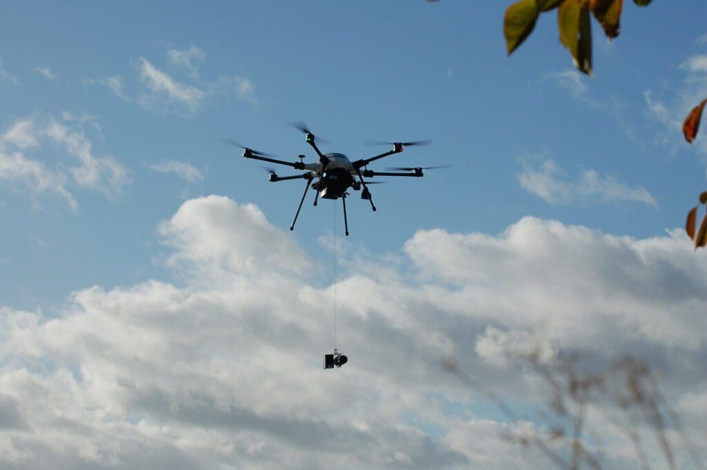 A helicopter is flying in the sky with a rope attached to it.