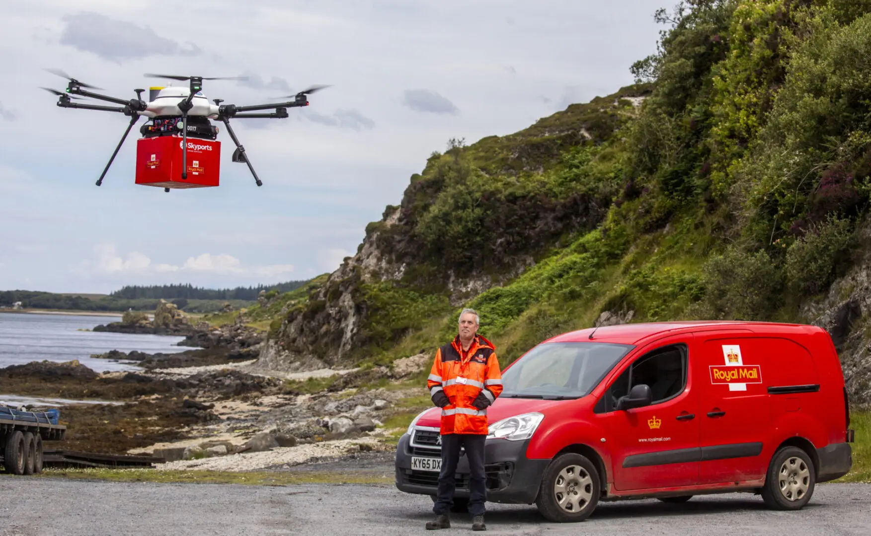 Jura postie Graeme Lindsay collects the mail from drone test flight from Islay.
Royal Mail has launched its latest trial to deliver mail by drone, in collaboration with drone specialists Skyports and Argyll and Bute Council.

The drone flights are running between the remote isles of Islay and Jura in the Inner Hebrides for a month until 26 July, with postal workers loading and unloading mail on both sides for the first time.

The multirotor drone, which can carry payloads of up to 6kg, is the same one used in Royal Mail’s previous trial in Orkney. It will transport mail that is usually taken via ferry in a Royal Mail van.